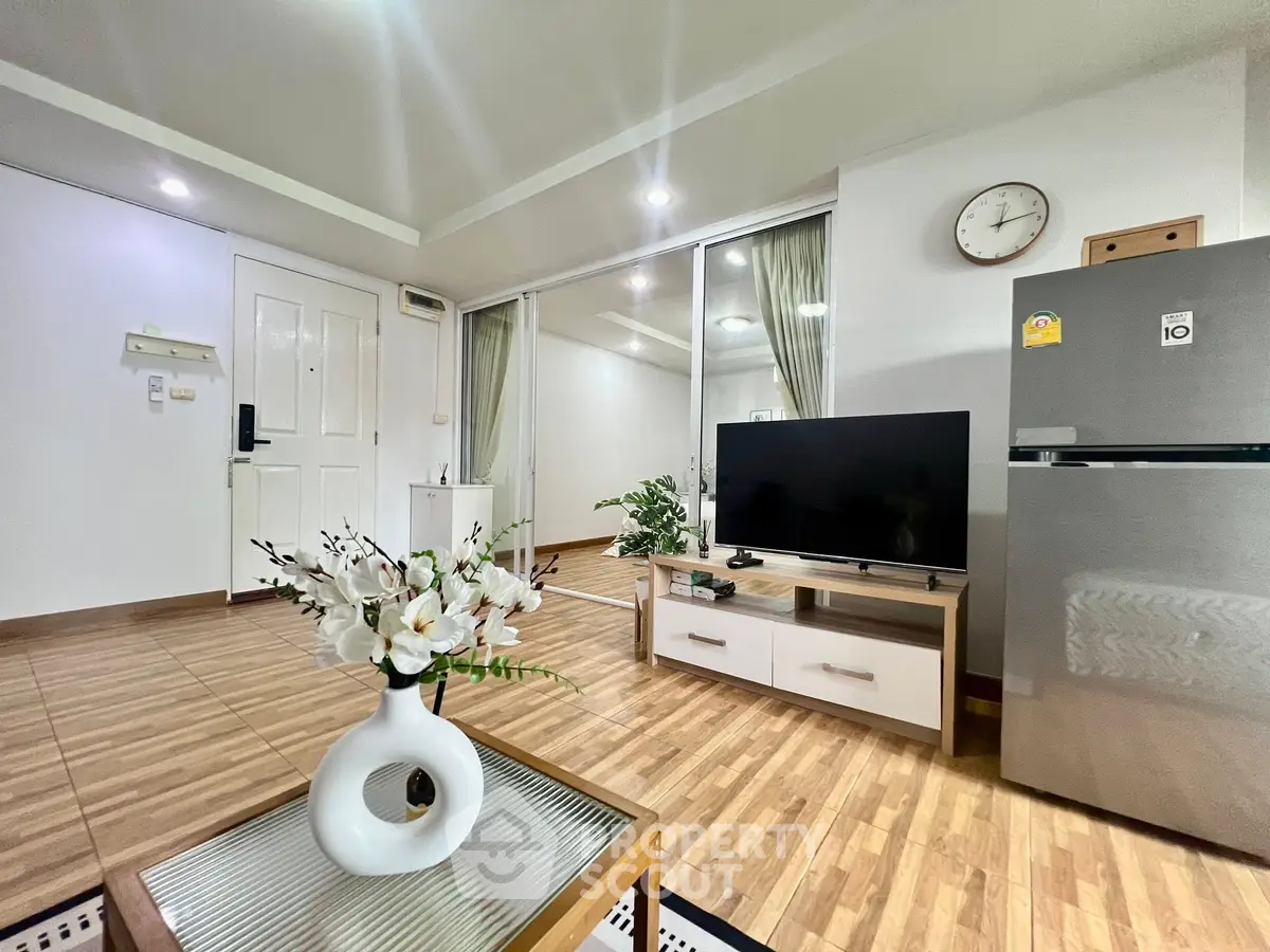 Modern living room with sleek decor and large TV, featuring wooden flooring and stylish furniture.