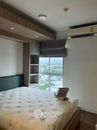 Modern bedroom with large window and built-in storage, offering a scenic view.