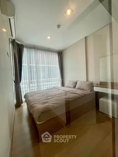 Modern bedroom with large window and stylish decor in a contemporary apartment.