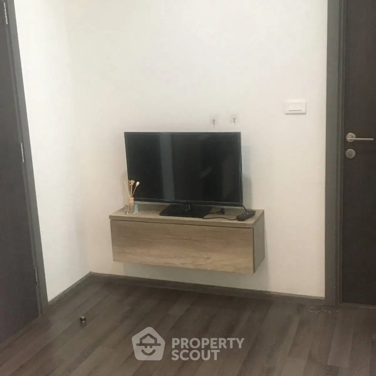 Modern living room corner with mounted TV and sleek wooden flooring.