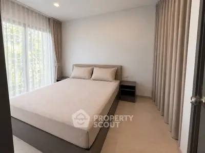 Modern bedroom with large window and neutral decor, perfect for relaxation and comfort.