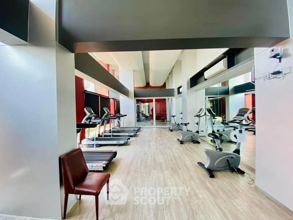 Spacious modern gym with state-of-the-art equipment and mirrored walls in luxury building.