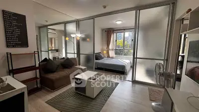 Modern studio apartment with glass partition, cozy living area, and bright bedroom with large window.