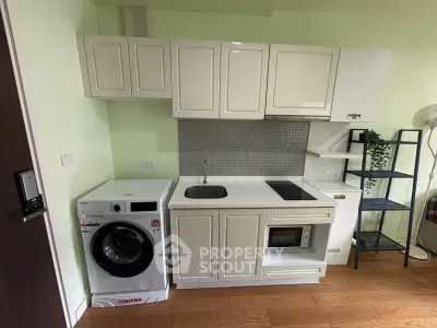 Compact modern kitchen with integrated appliances and washing machine in a cozy apartment.