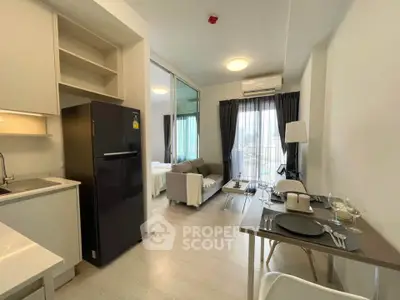 Modern open-plan apartment with sleek kitchen and cozy living area, featuring large windows and stylish decor.