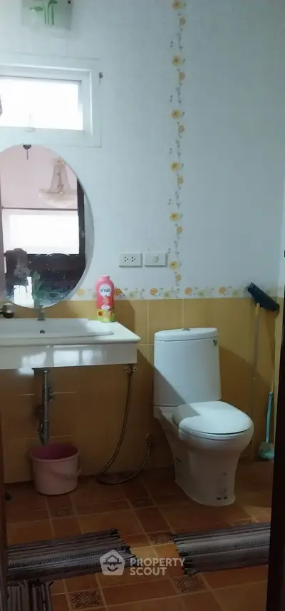 Cozy bathroom with modern toilet and sink, featuring floral wall accents and tiled flooring.