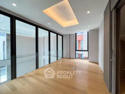 Spacious modern living area with floor-to-ceiling windows and elegant wooden flooring.
