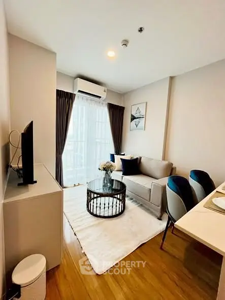 Chic modern living room with cozy sofa, stylish decor, and natural light from large window.