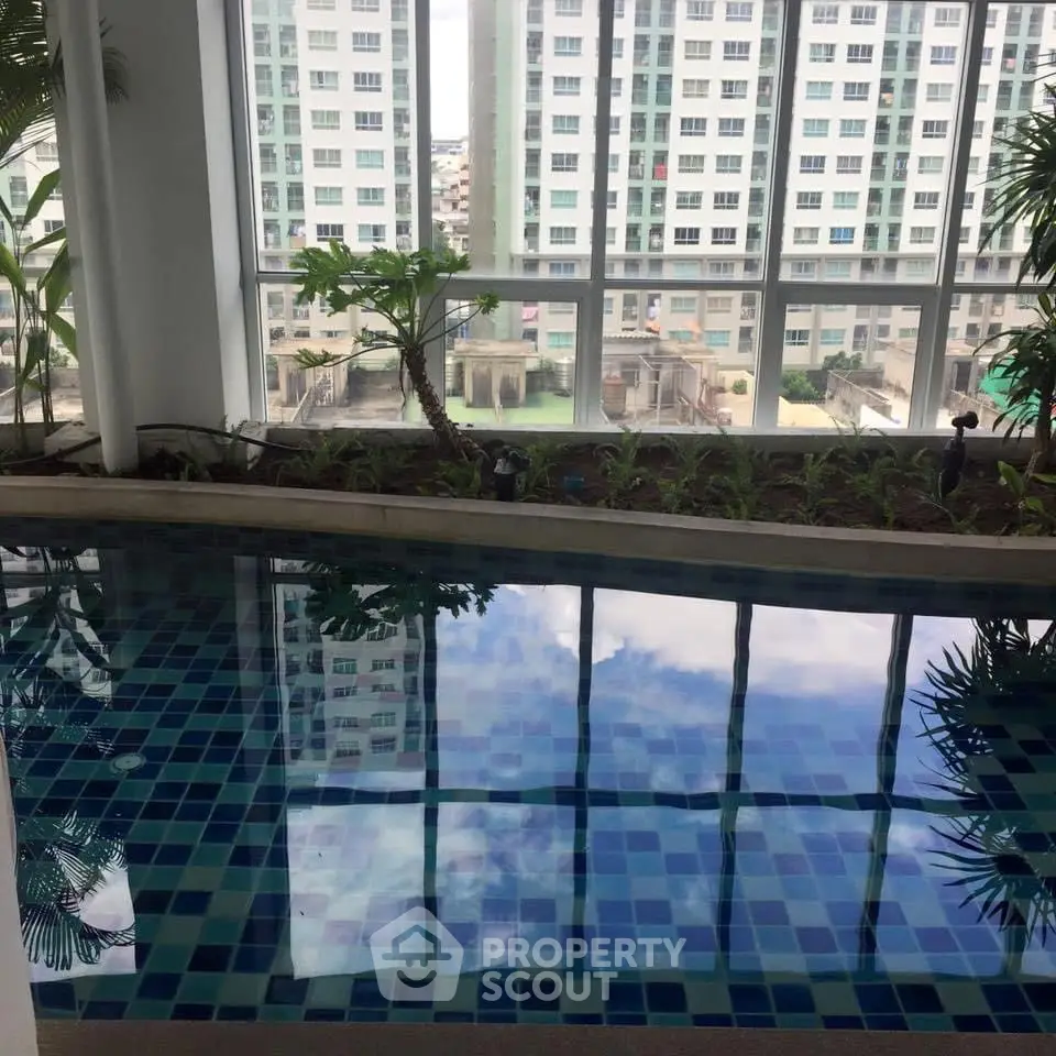 Luxurious indoor pool with city view in modern high-rise building.