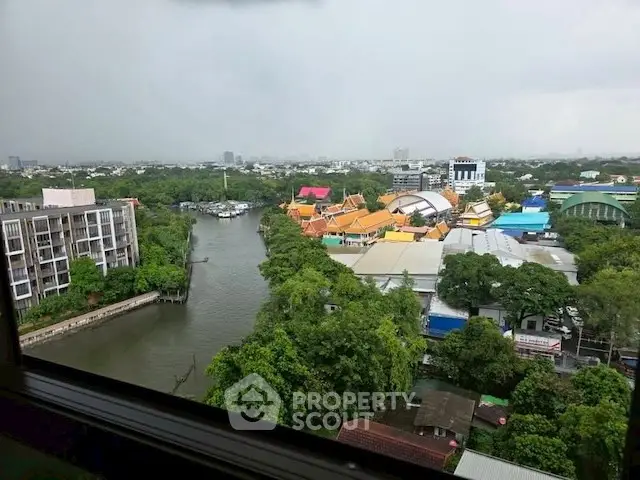 Stunning river view from high-rise apartment window showcasing vibrant cityscape and lush greenery.