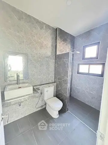 Modern bathroom with sleek gray tiles and a walk-in shower design.