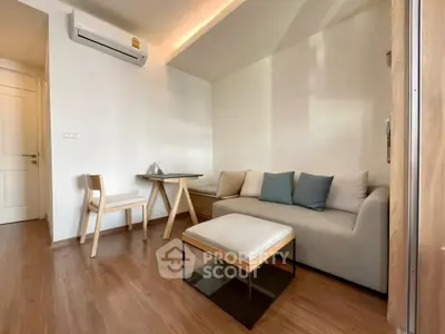 Modern living room with cozy sofa, wooden flooring, and air conditioning in a stylish apartment.