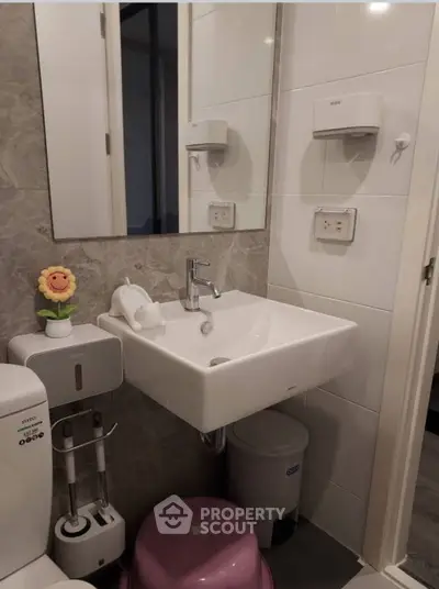 Modern bathroom with sleek sink and toilet, stylish decor, and efficient use of space.
