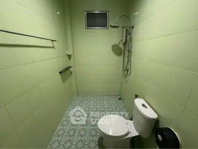 Spacious green-tiled bathroom with modern shower and toilet
