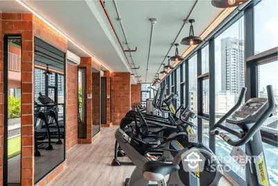 Modern gym with city view and state-of-the-art equipment in luxury apartment building.