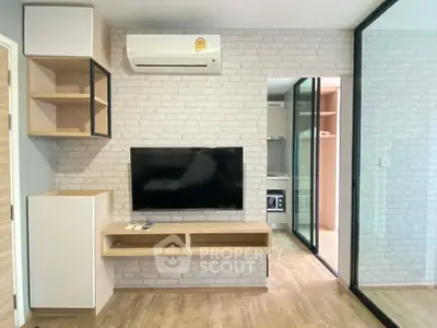 Modern living room with TV, air conditioning, and stylish shelving on brick accent wall.
