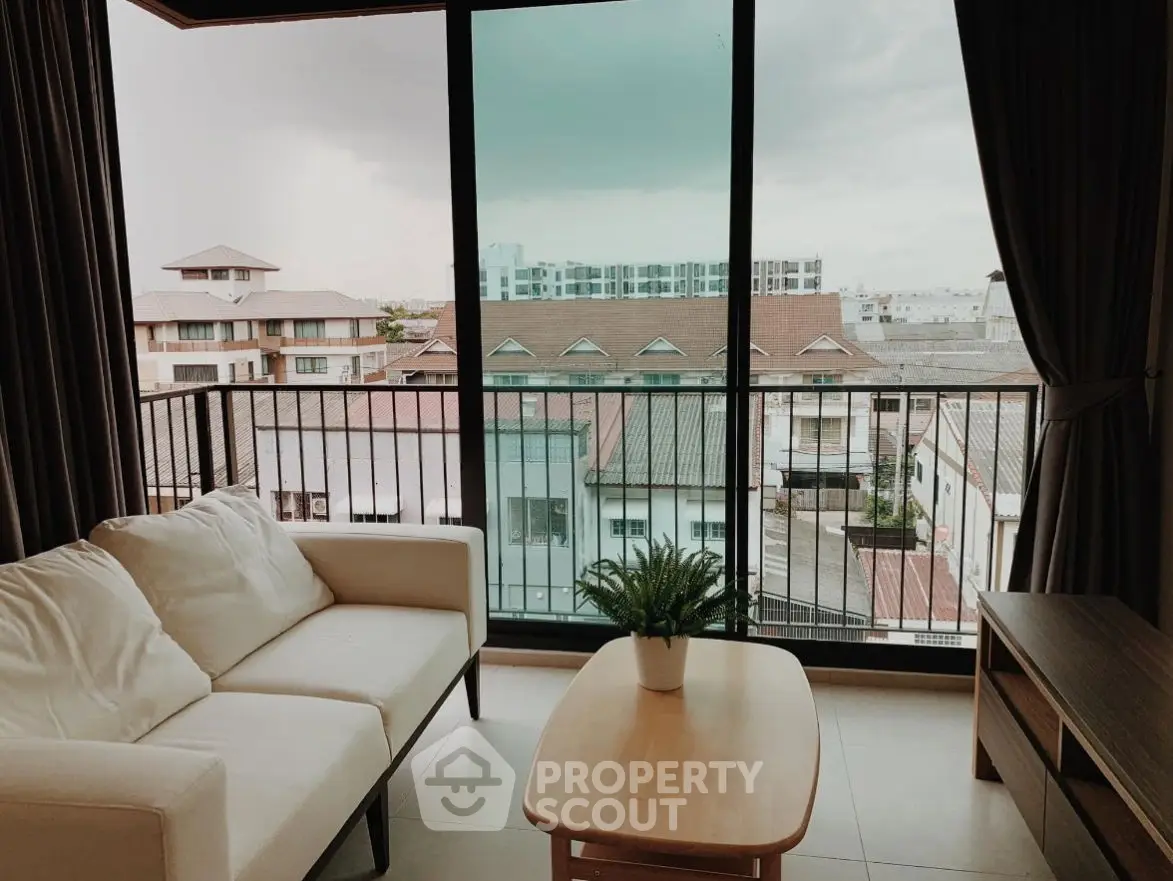 Cozy living room with balcony view overlooking urban landscape.