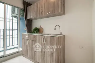 Modern compact kitchen with wooden cabinets and balcony view