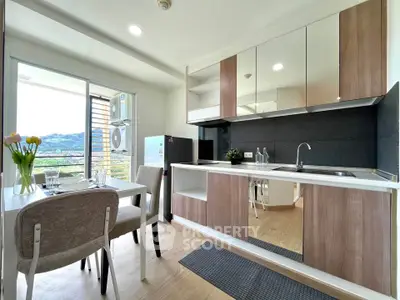Modern kitchen with open layout and dining area, featuring sleek cabinets and scenic view.