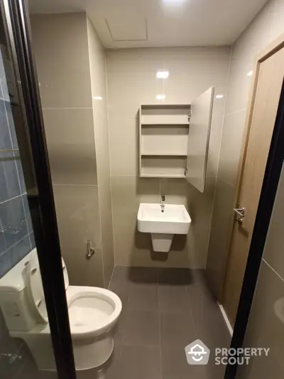 Modern bathroom with sleek fixtures, neutral tiles, and a glass shower enclosure, offering a clean and contemporary space for relaxation.