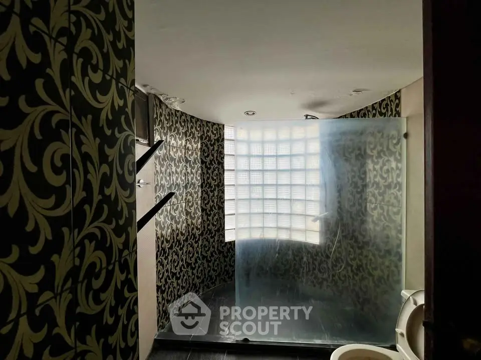 Luxurious bathroom with elegant wallpaper and frosted glass shower in modern home.
