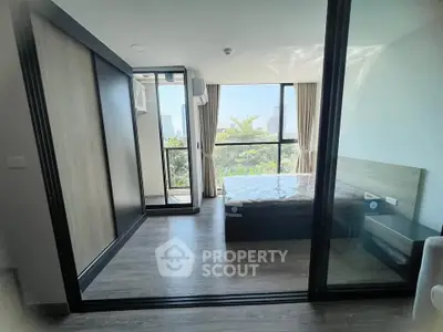 Modern bedroom with large windows and balcony access in a stylish apartment.
