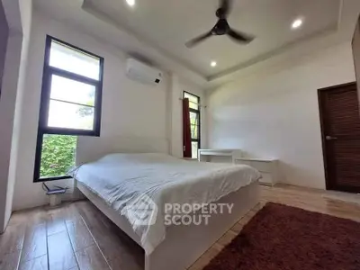 Spacious bedroom with modern design, featuring large windows and wooden flooring.