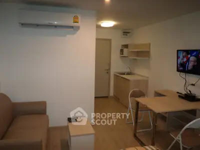 Modern compact living room with kitchenette, featuring air conditioning and cozy seating area.