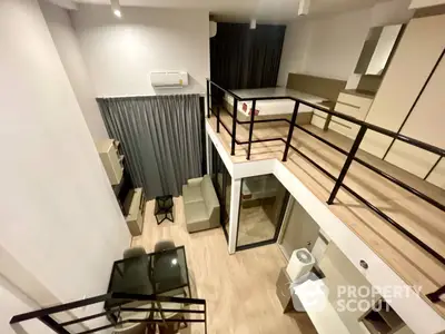 Modern duplex apartment with sleek furnishings and a spacious, open layout, featuring a unique mezzanine level and large windows for ample natural light.