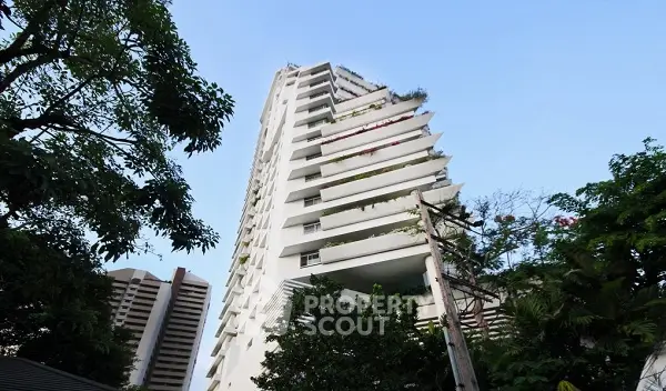 Modern high-rise building with lush greenery and clear blue sky