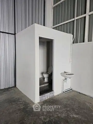 Minimalist industrial bathroom with exposed concrete and metal walls.