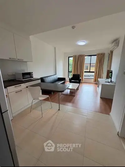 Modern open-plan living room with sleek kitchen and stylish furniture, featuring large windows for natural light.