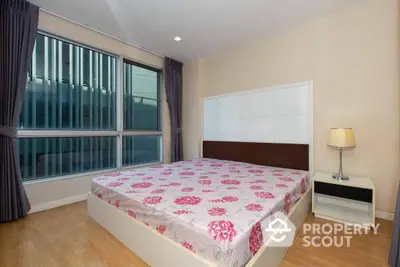 Spacious bedroom with large windows and modern decor in a stylish apartment.