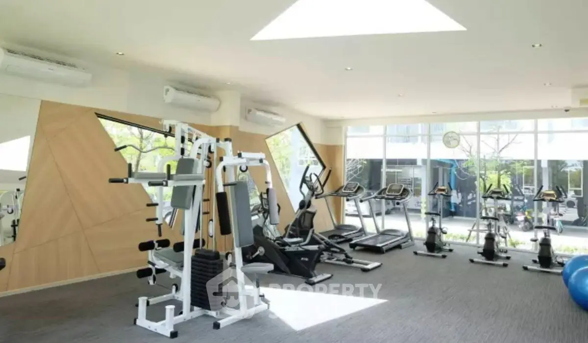 Modern gym with state-of-the-art fitness equipment and large windows for natural light.