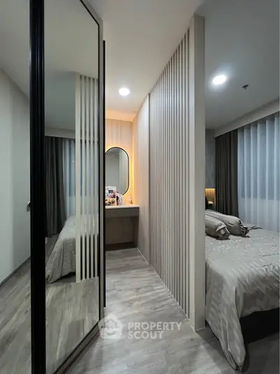 Modern bedroom with stylish partition and cozy lighting, featuring a large mirror and elegant decor.