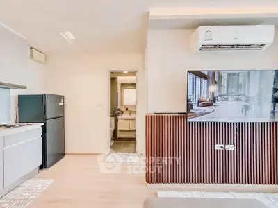 Modern apartment interior with sleek kitchen and stylish living area featuring a wall-mounted TV and air conditioning.