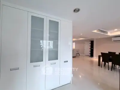 Spacious modern living room with sleek white cabinetry and elegant dining area.