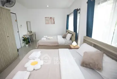 Spacious bedroom with two cozy beds, modern decor, and ample natural light.