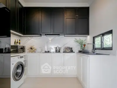 Modern kitchen with sleek black and white cabinetry, marble backsplash, and built-in washing machine.