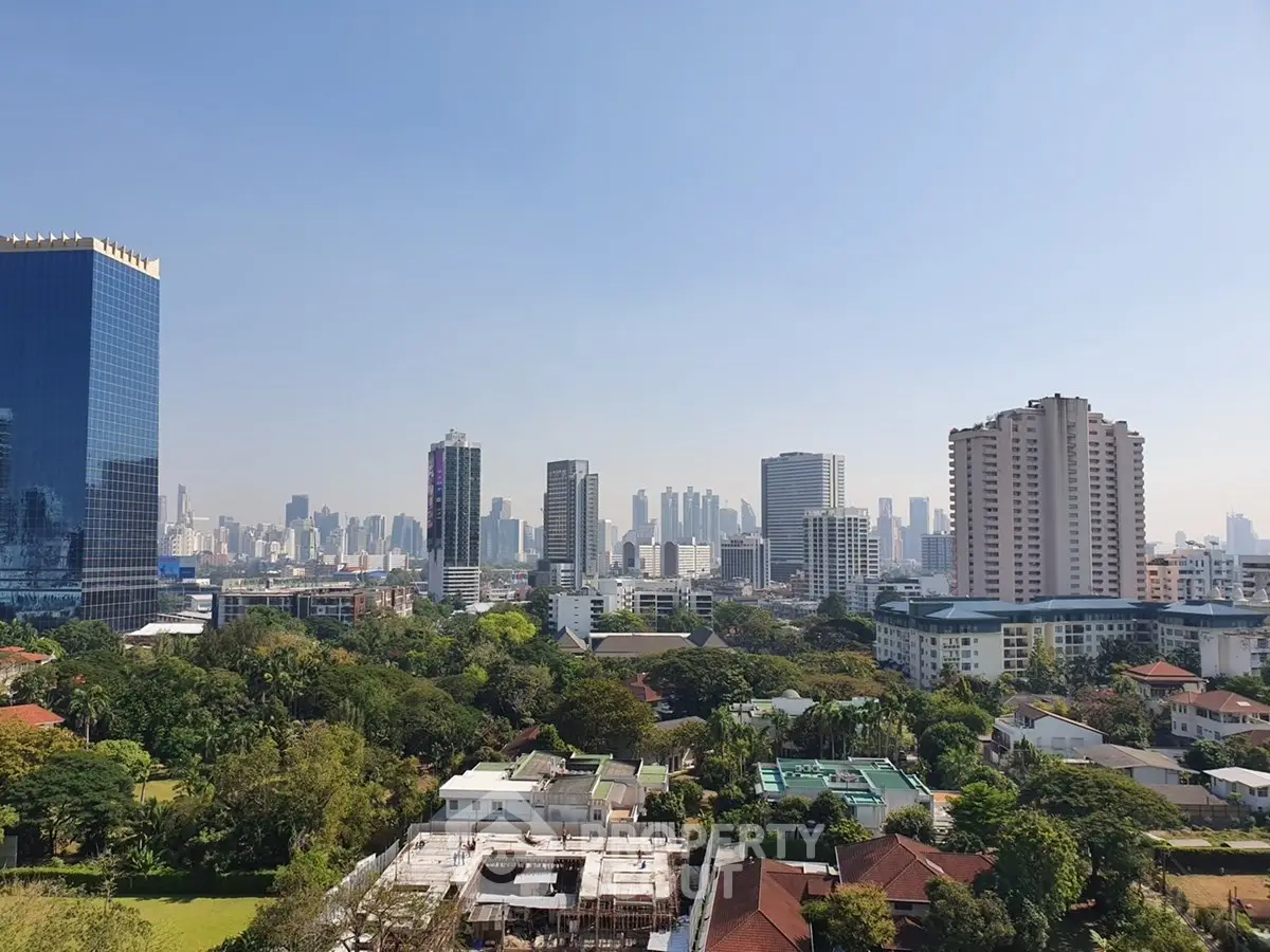 Stunning cityscape view with lush greenery and modern high-rise buildings under a clear blue sky.