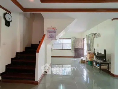 Spacious living area with staircase and natural light, ideal for family gatherings.
