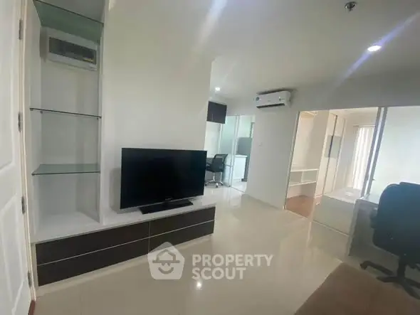 Modern living room with sleek TV setup and air conditioning in a bright apartment.