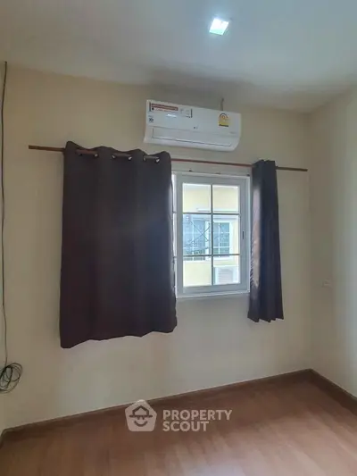 Cozy bedroom with air conditioning and wooden flooring, perfect for comfort and relaxation.