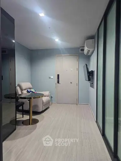 Modern living room with sleek design, featuring a cozy armchair, wall-mounted TV, and stylish flooring.