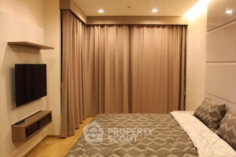 Cozy bedroom with modern decor and wall-mounted TV in a stylish apartment.
