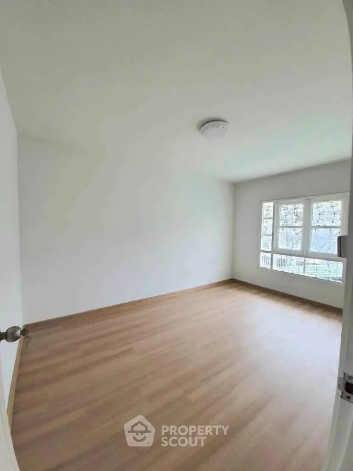 Spacious empty room with large windows and wooden flooring, perfect for customization.