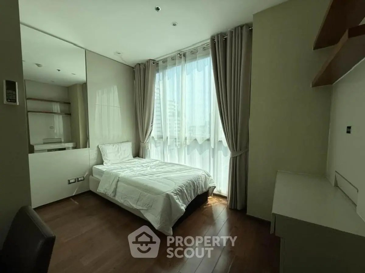 Cozy bedroom with large window and modern furnishings in urban apartment