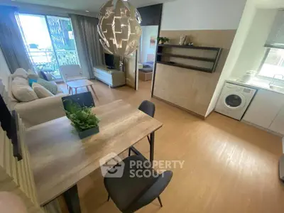 Modern open-plan living room with stylish decor and in-unit laundry, featuring a cozy dining area and balcony access.