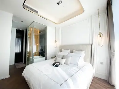 Luxurious modern bedroom with elegant lighting and glass-enclosed bathroom.