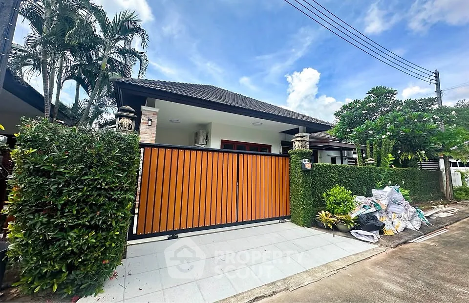 Charming single-story home with modern gate and lush greenery in a serene neighborhood.
